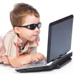 a boy in the sunglasses is typing on a laptop